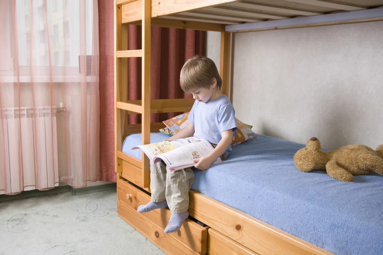 Kleiner Junge liest ein Buch im Kinderzimmer