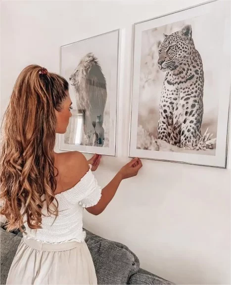 Junges Mädchen hängt zwei Bilder mit Tiger und Löwen