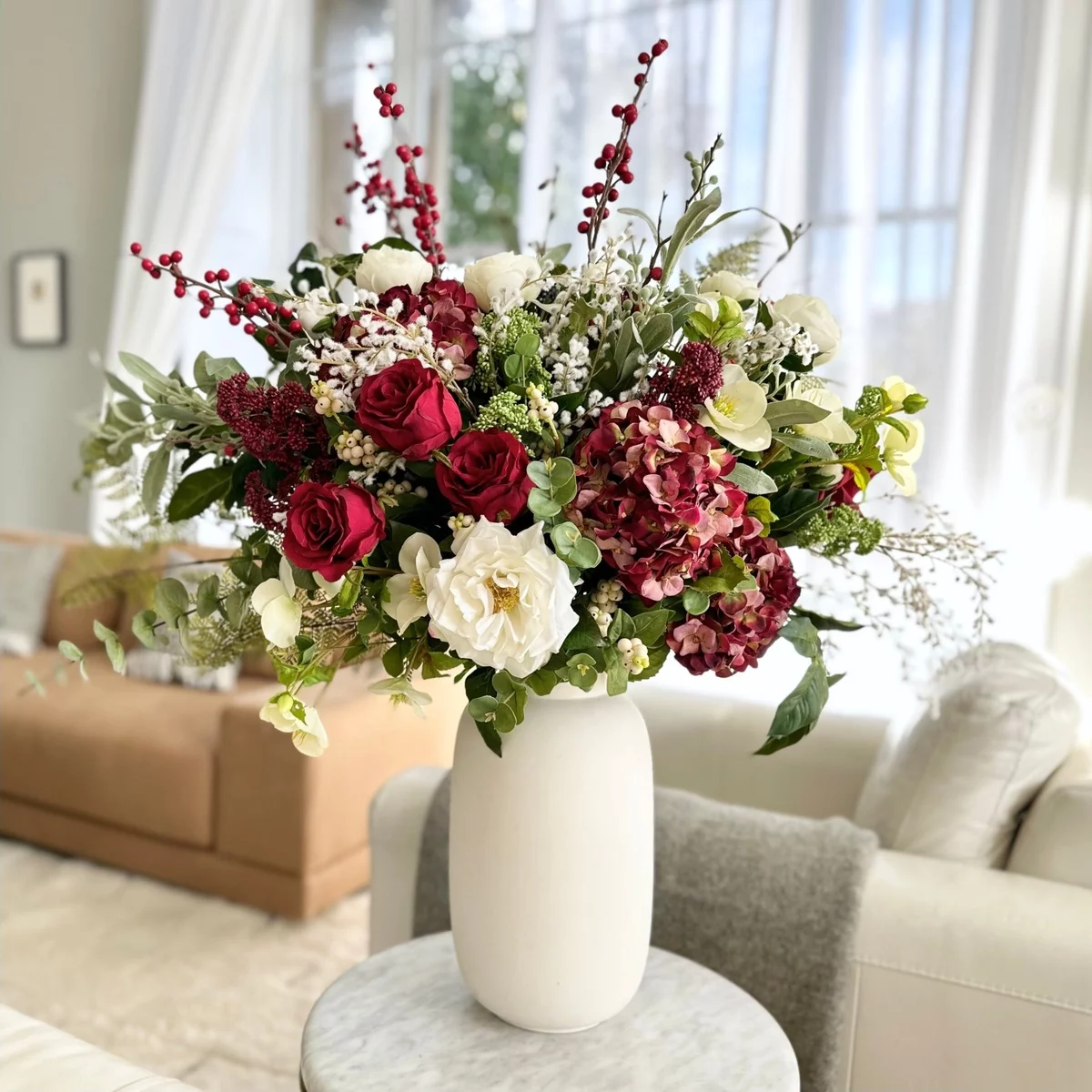 üppges künstliches Blumenarrangement in weißer Vase im Wohnzimmer