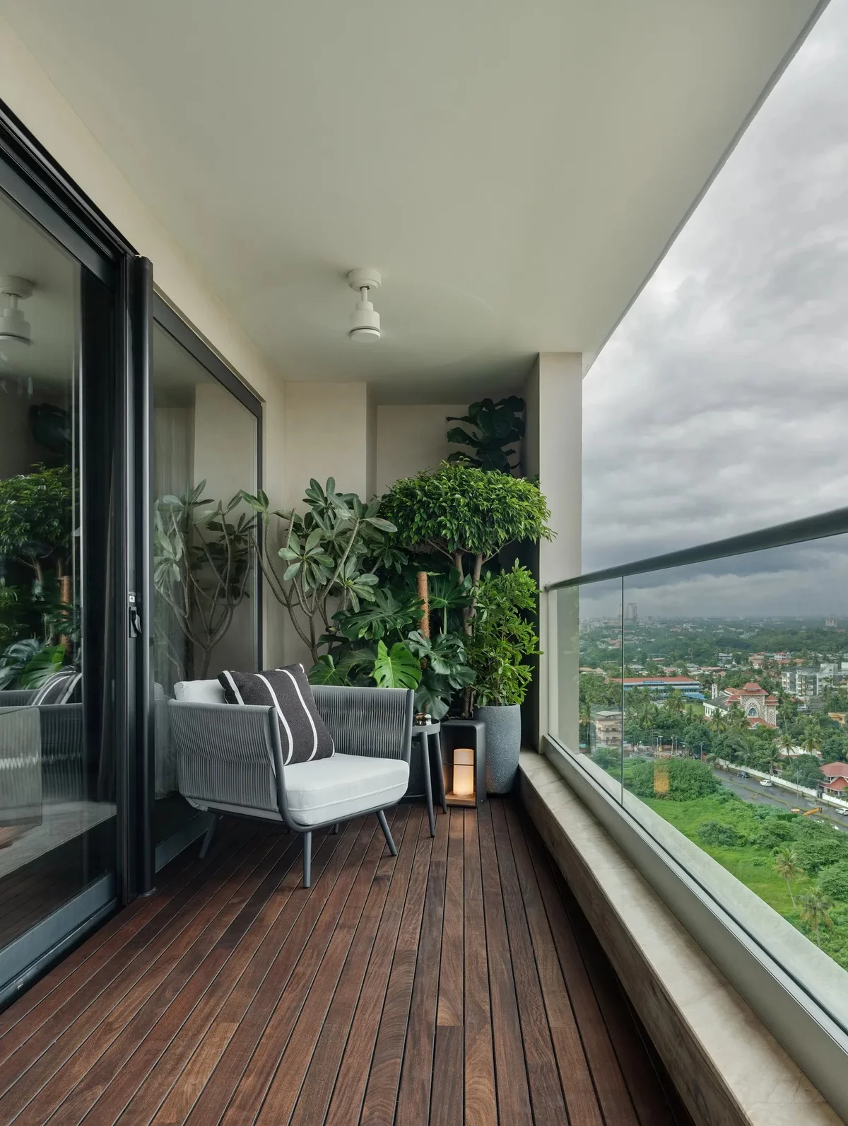 moderner Balkon mit Holzboden, Sessel und grünen Topfpflanzen 