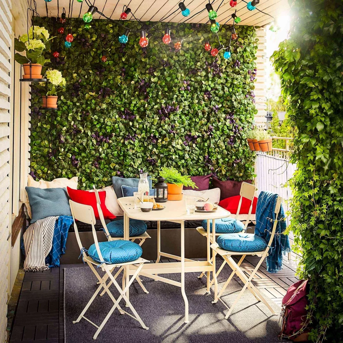 grüne Wand und einfache Balkonmöbel mit bunten Sitzkissen
