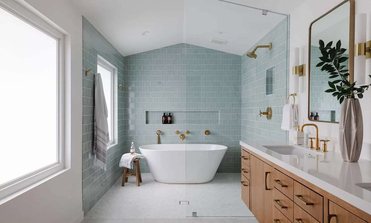 modernes Bad mit Badewanne und großem Fenster, in einer hellblauer Nuance gestaltet