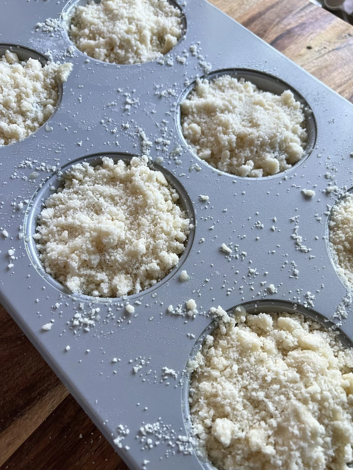 Blaubeermuffins mit Streuseln in der Backform gehen in den Backofen