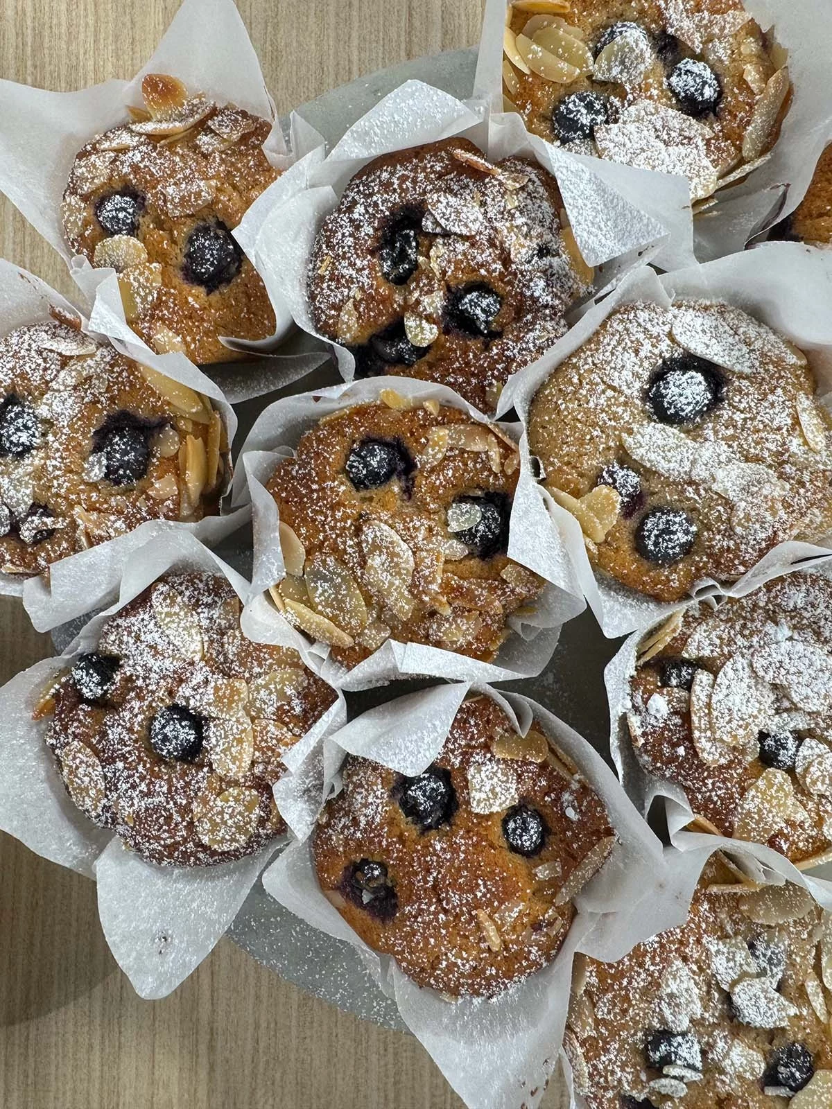 Blaubeermuffins mit Puderzucker und Mandeln darauf