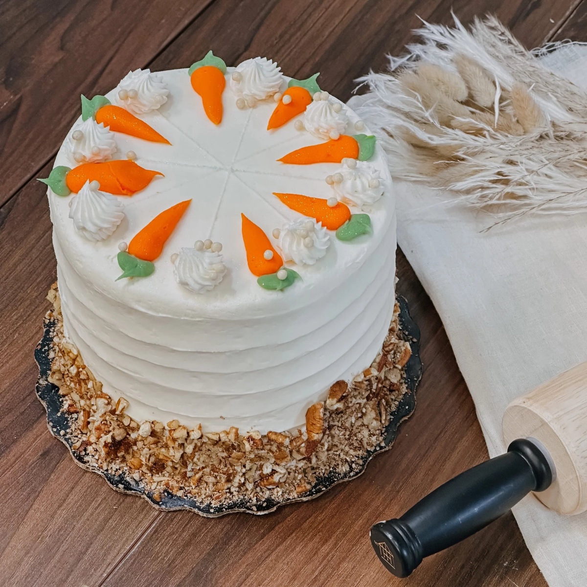 runder Karottenkuchen mit weißem Frischkäse-Frosting und kleinen Möhren 