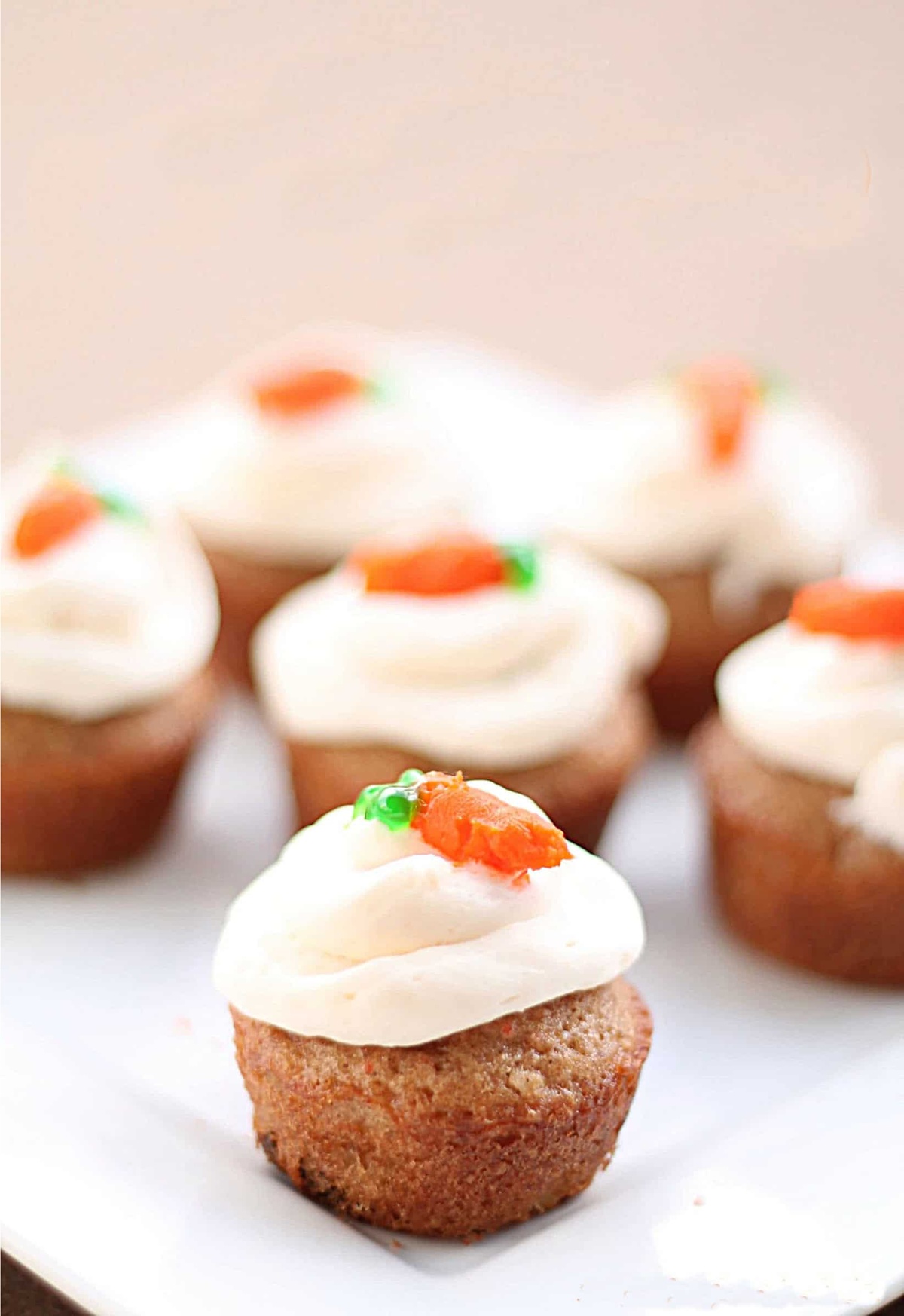 Karotten-Muffins mit weißem Frosting und einer Möhre als Deko 