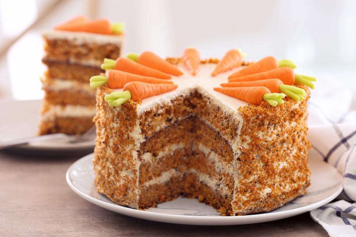 runder Karottenkuchen in Schichten und mit kleinen Möhren oben dekoriert 