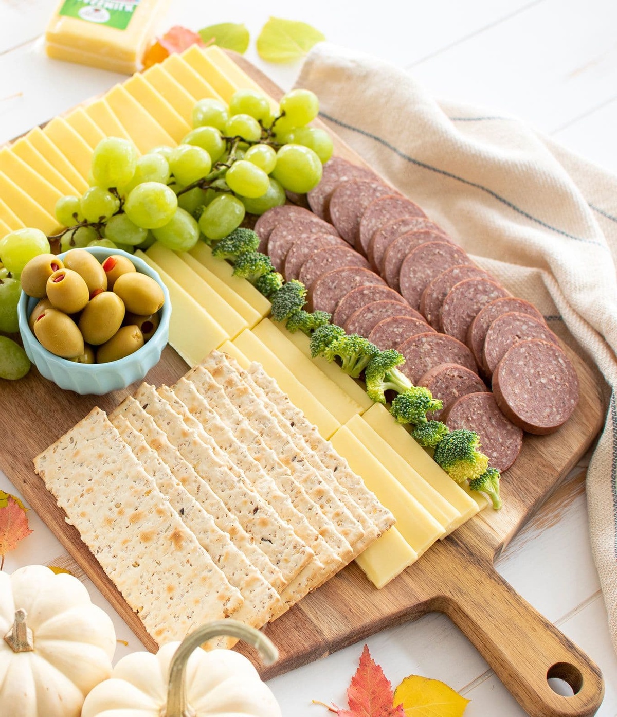 Oliven, Trauben, Cracker, Käse und Wurst auf einem Holzbrett