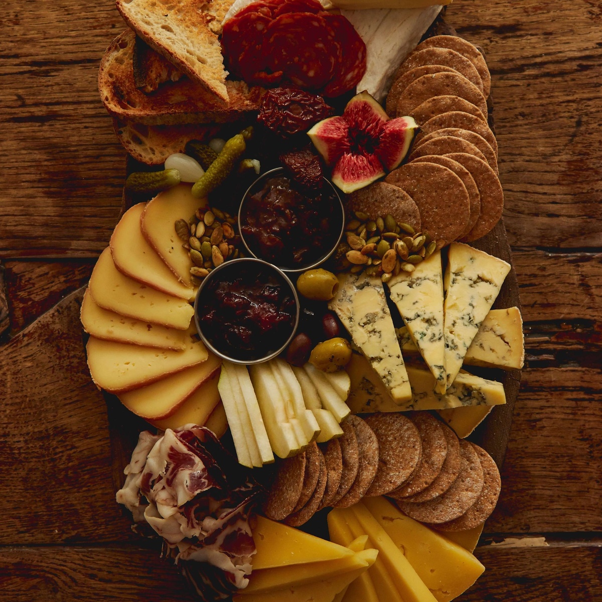 Käse mit Cracker, Salami und Marmelade auf dem Holzbrett kombinieren