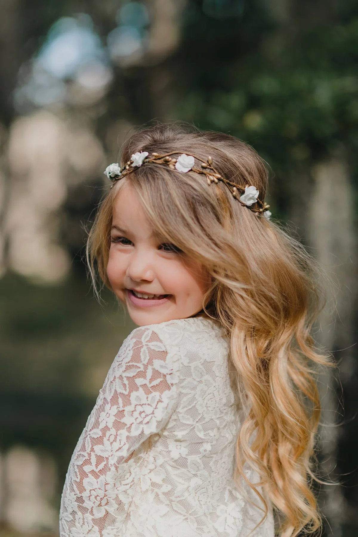 fröhliches Mädchen mit Blumenkranz im Haar 