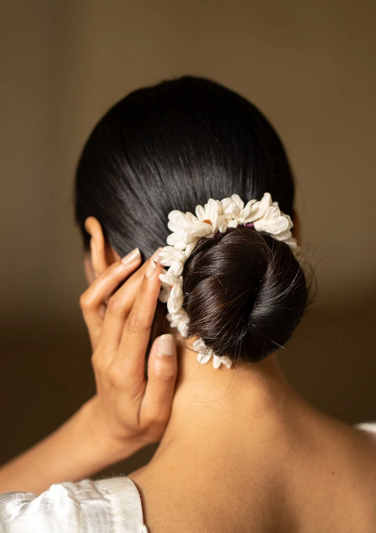 Der weiße Blumenkranz steht gut im schwarzen Haar 