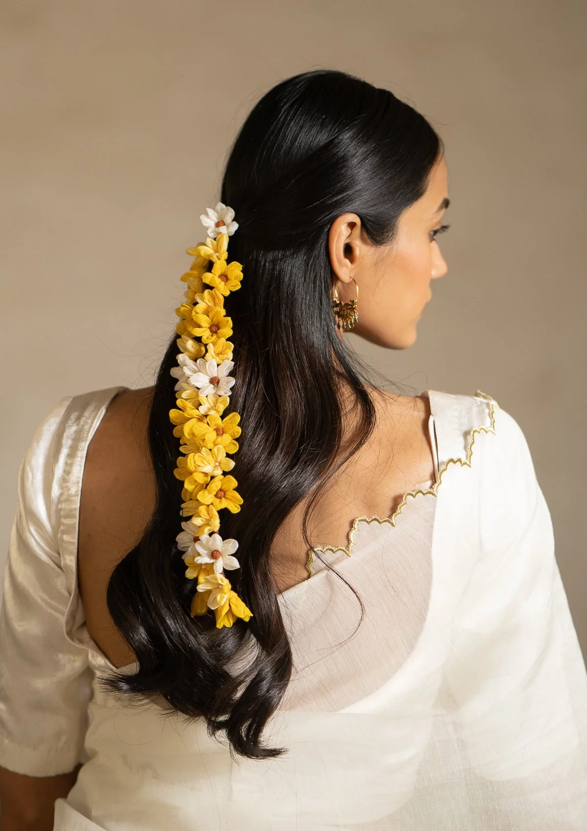 zarte Blüten aus Seide in Weiß und Gelb schmücken das schwarze Haar 