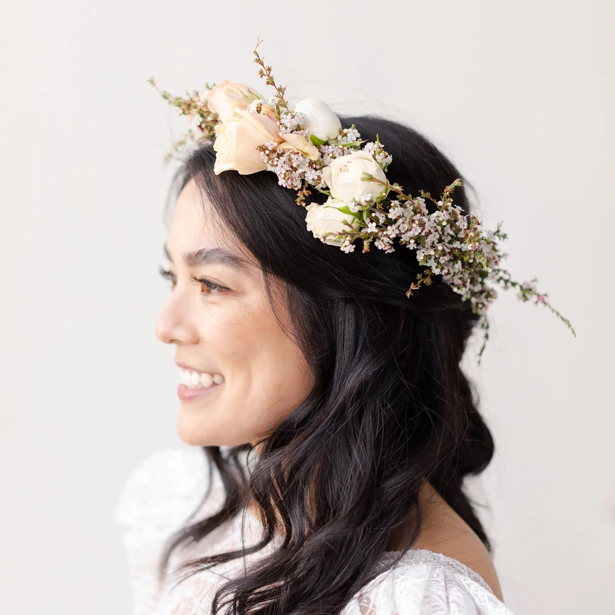 Blumen im Haar - junge Frau mit dunklem Haar trägt Blumenkranz auf der Hochzeit 