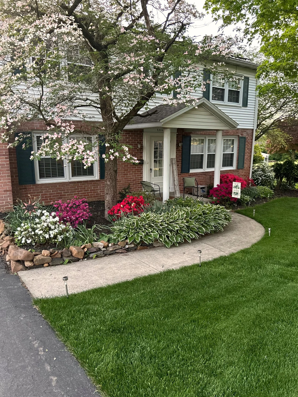 Hosta und bunt blühende Blumen in einem gut geformten Blumenbeet - Vorgarten Ideen