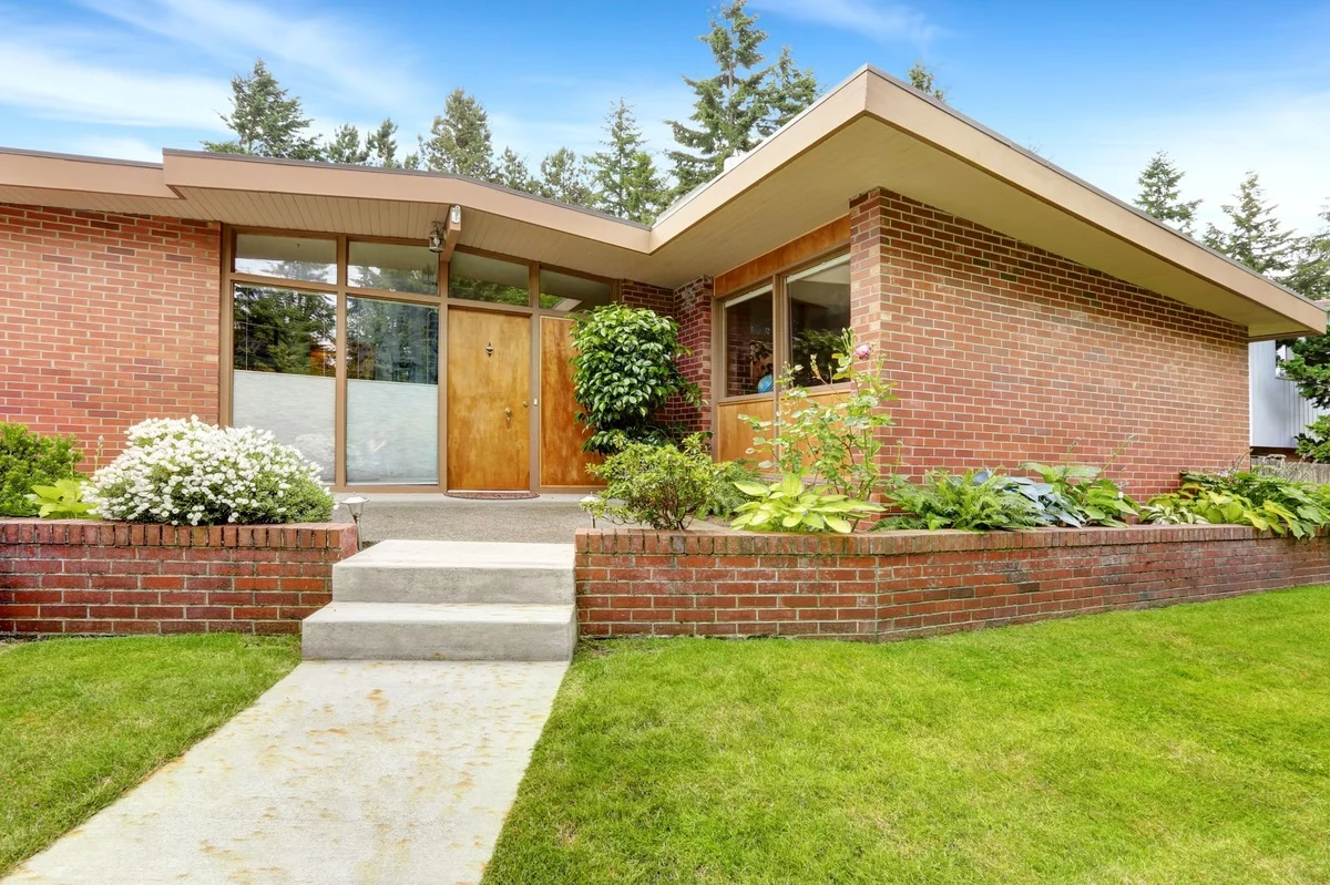 einstöckiges Haus mit Flachdach hat einen stilvoll gestalteten Vorgarten