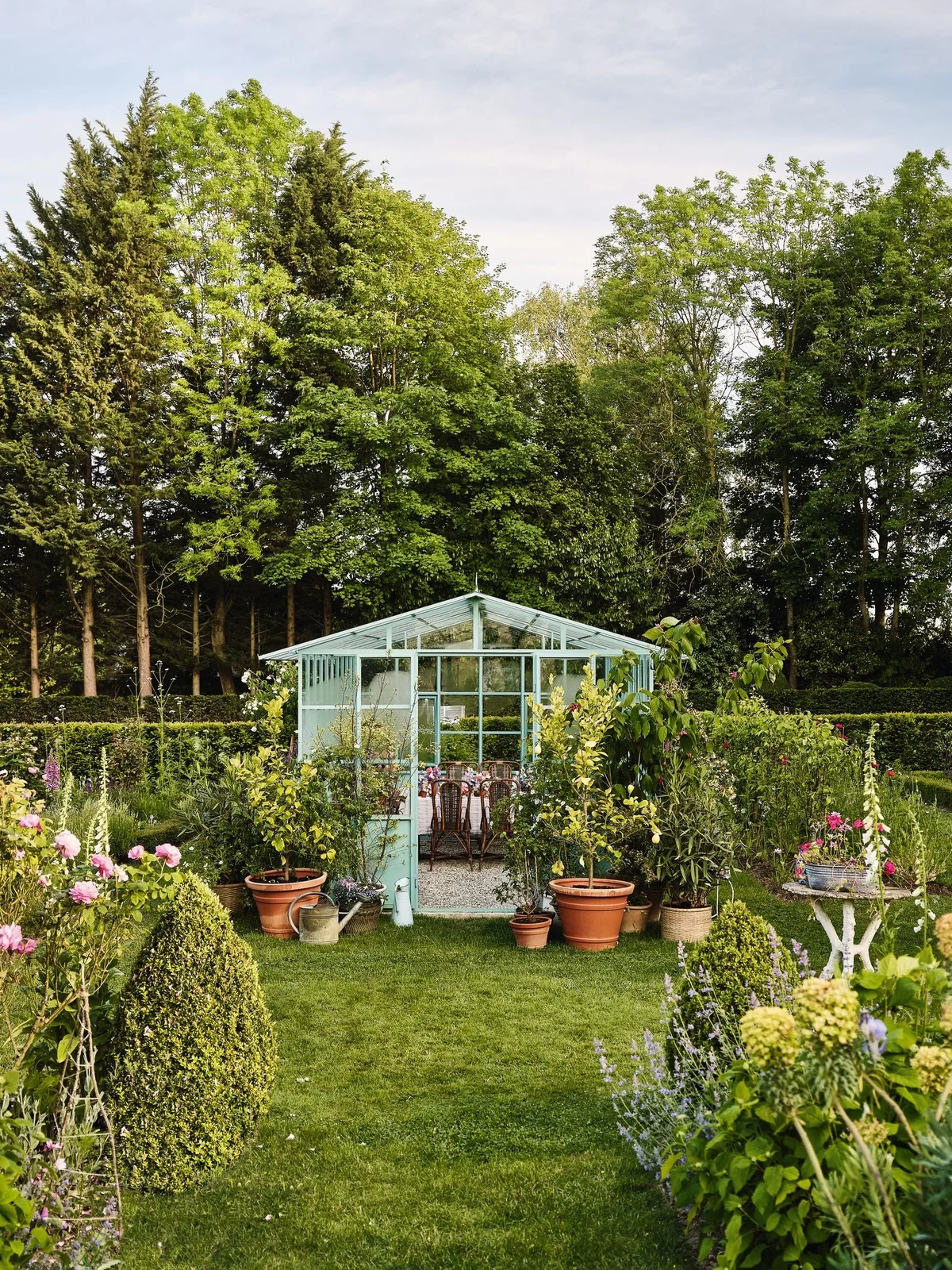 ein Gartenhaus aus Glas mit vielen Pflanzen ringsum