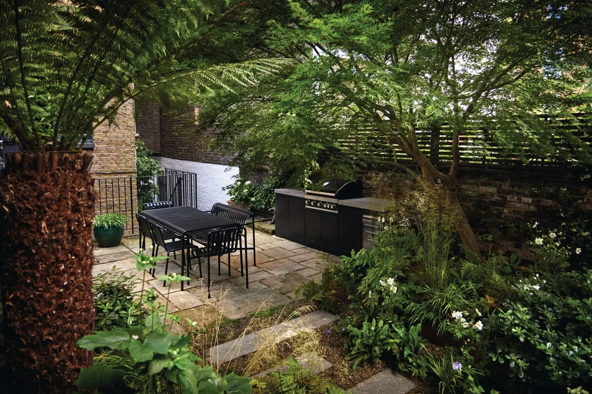 Essecke und Grillbereich mitten üppigen Pflanzen im Garten
