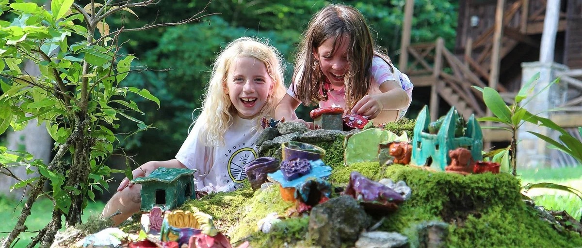 Gartenideen Kinder - zwei Mädchen spielen neben einem Hügel mit Deko 