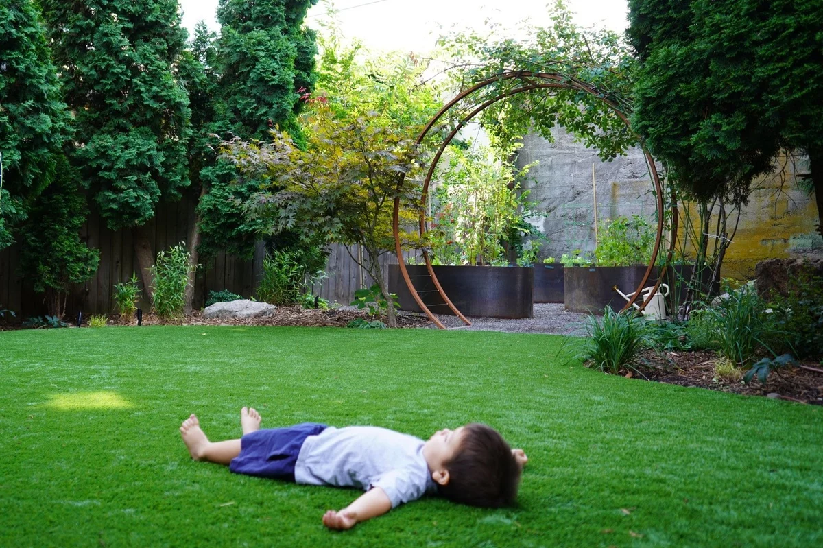Gartenideen Kinder - kleiner Junge liegt im Gras 