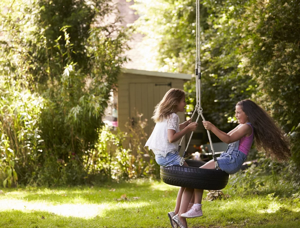 zwei Mädchen schakeln auf einem Autoreifen - Gartenideen Kinder