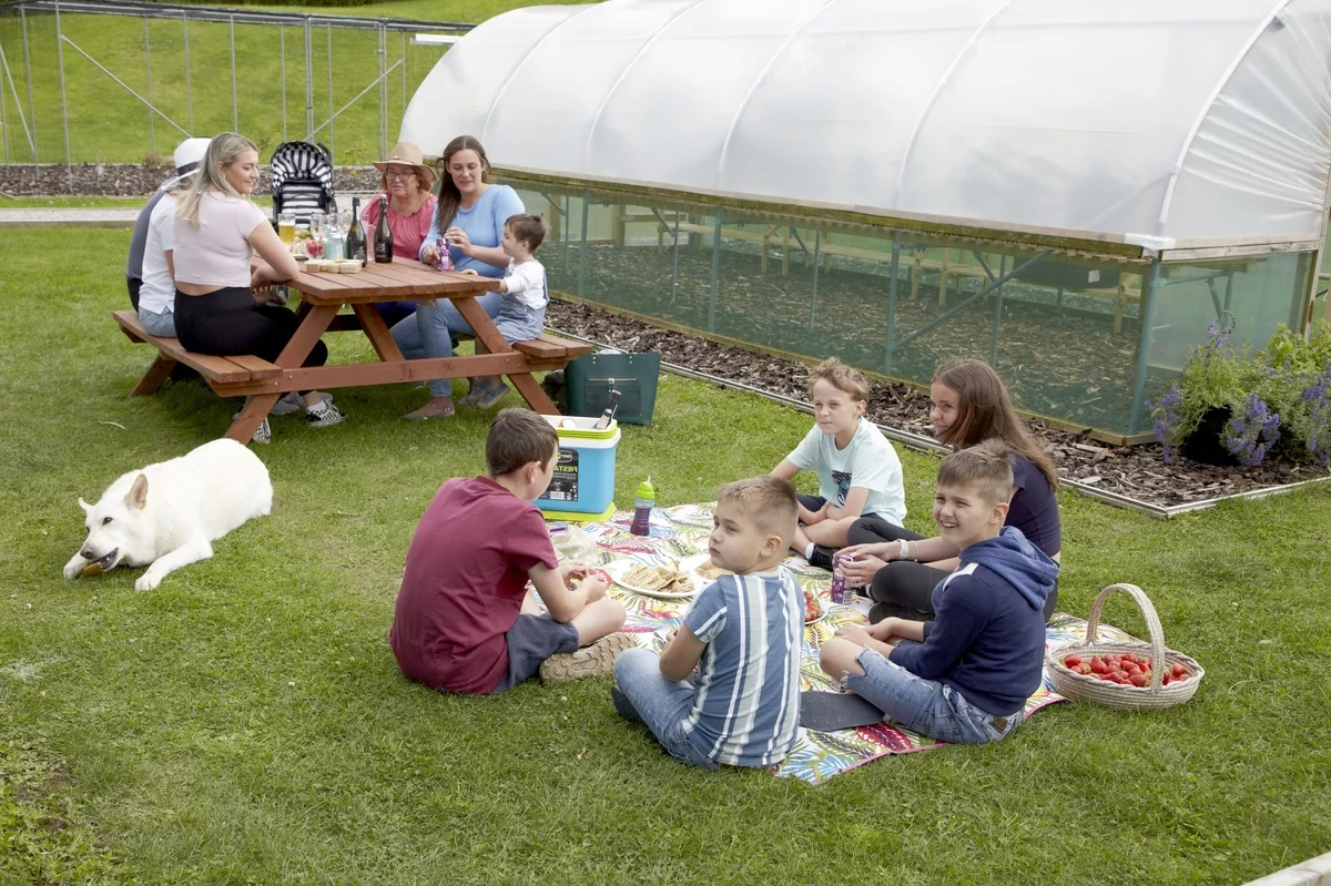 Picknick draußen im Garten - Kinder sitzen auf dem Gras und essen 