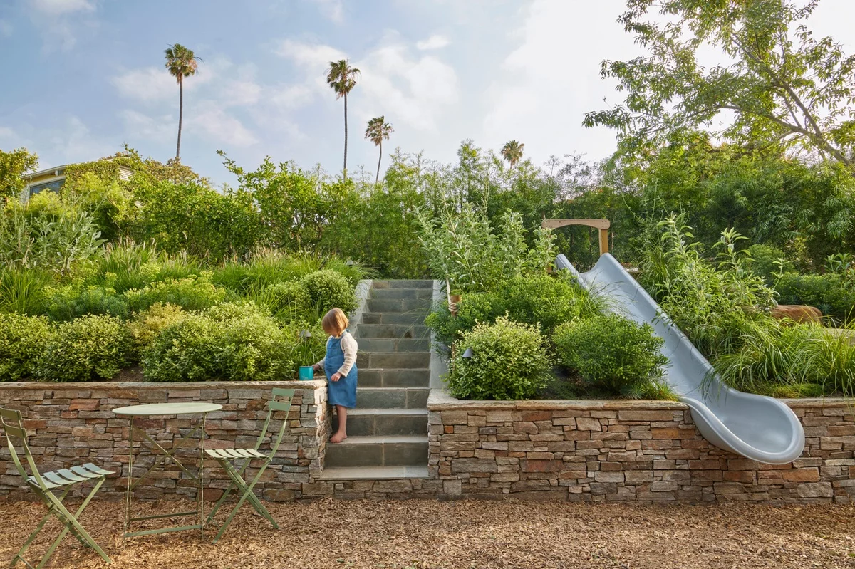 Rutsche im Garten und kleines Mädchen daneben 