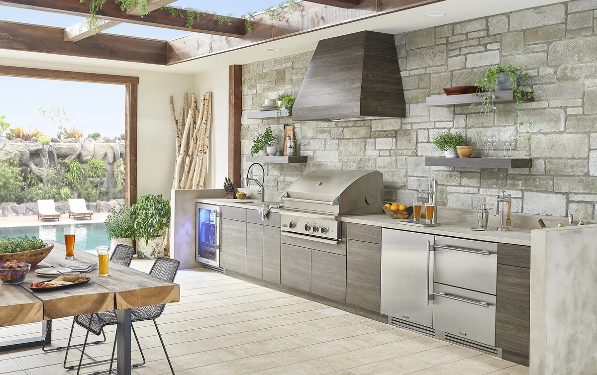 moderne Gartenküche gut ausgestattet vor einer Steinwand