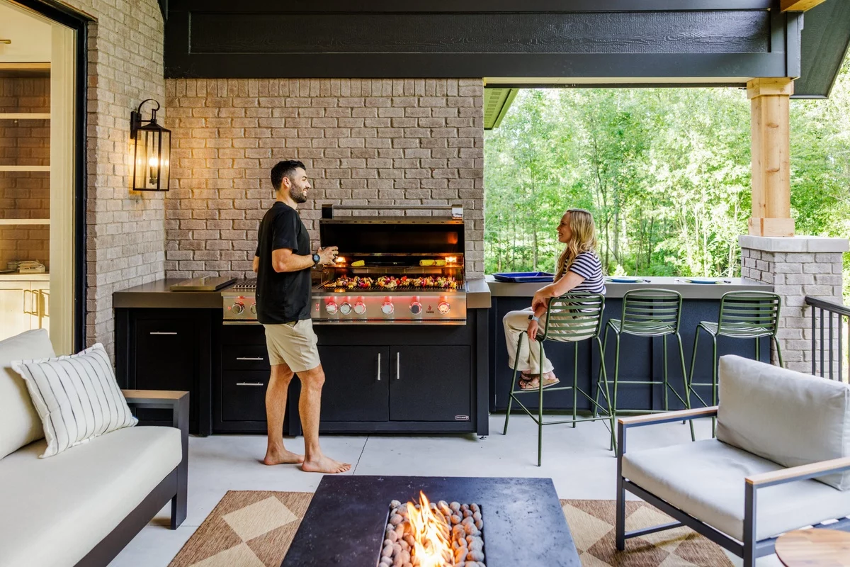 Mann und Frau beim Grillen in der Gartenküche
