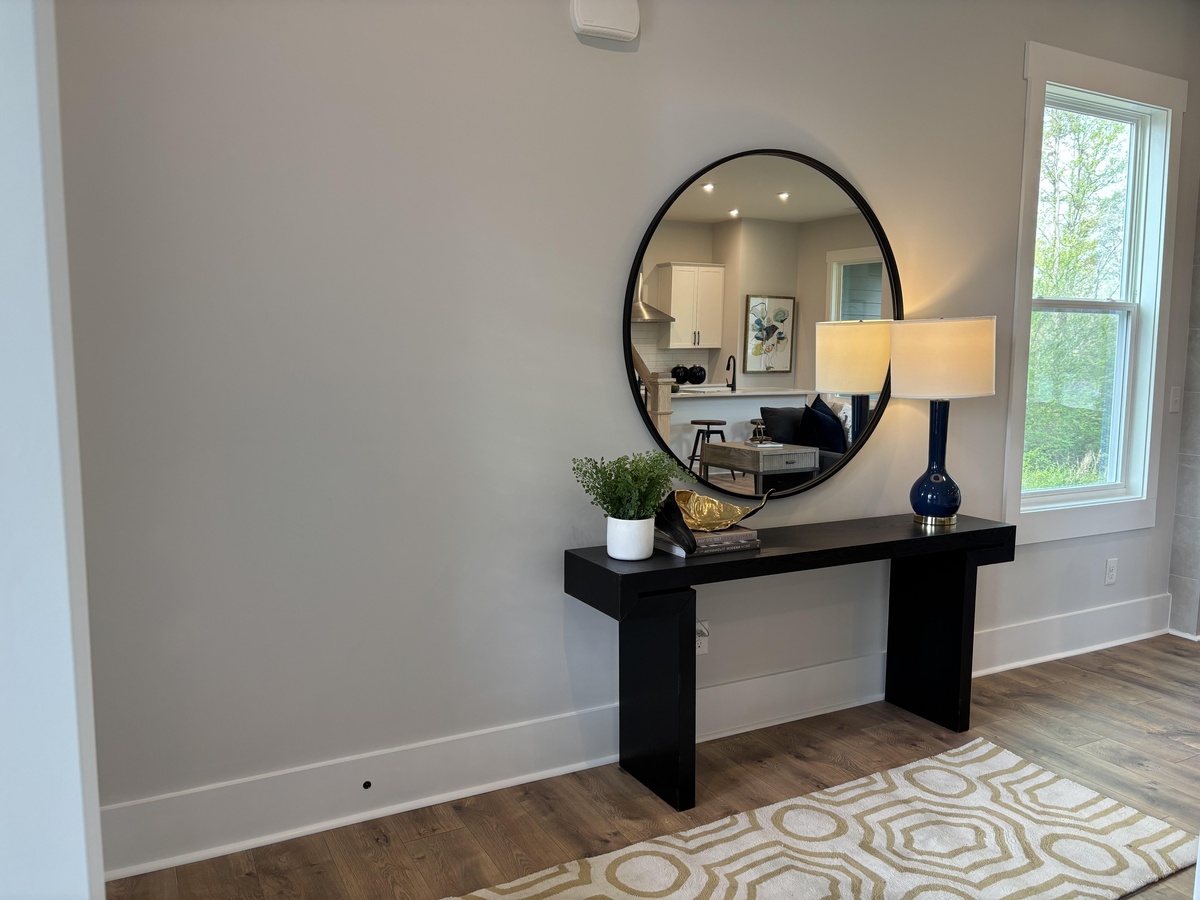 runder Wandspiegel und kleines Regal mit Lampe