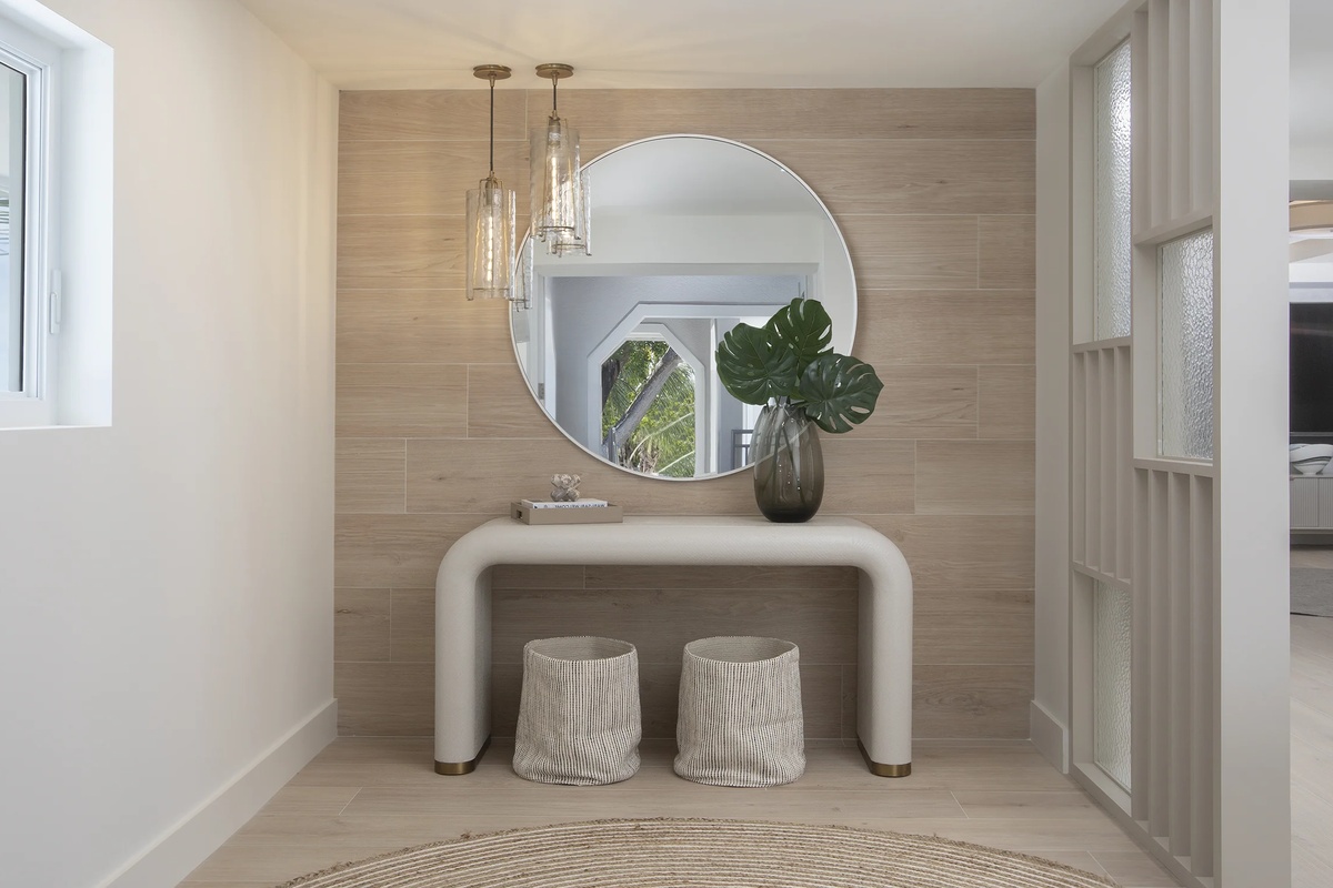 modern gestalteter Hauseingang mit rundem Spiegel und Vase mit grünen Blättern