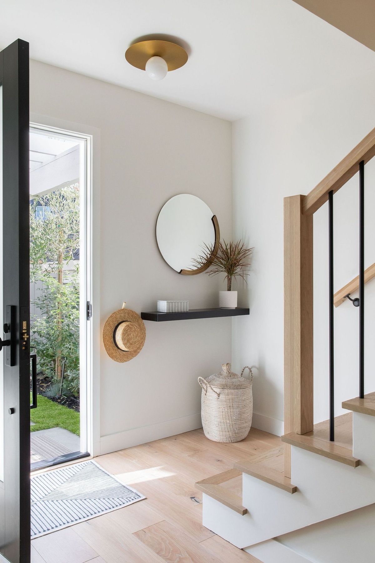kleinen Hauseingang gestalten mit rundem Wandspiegel und Holzregal - Treppe nach oben