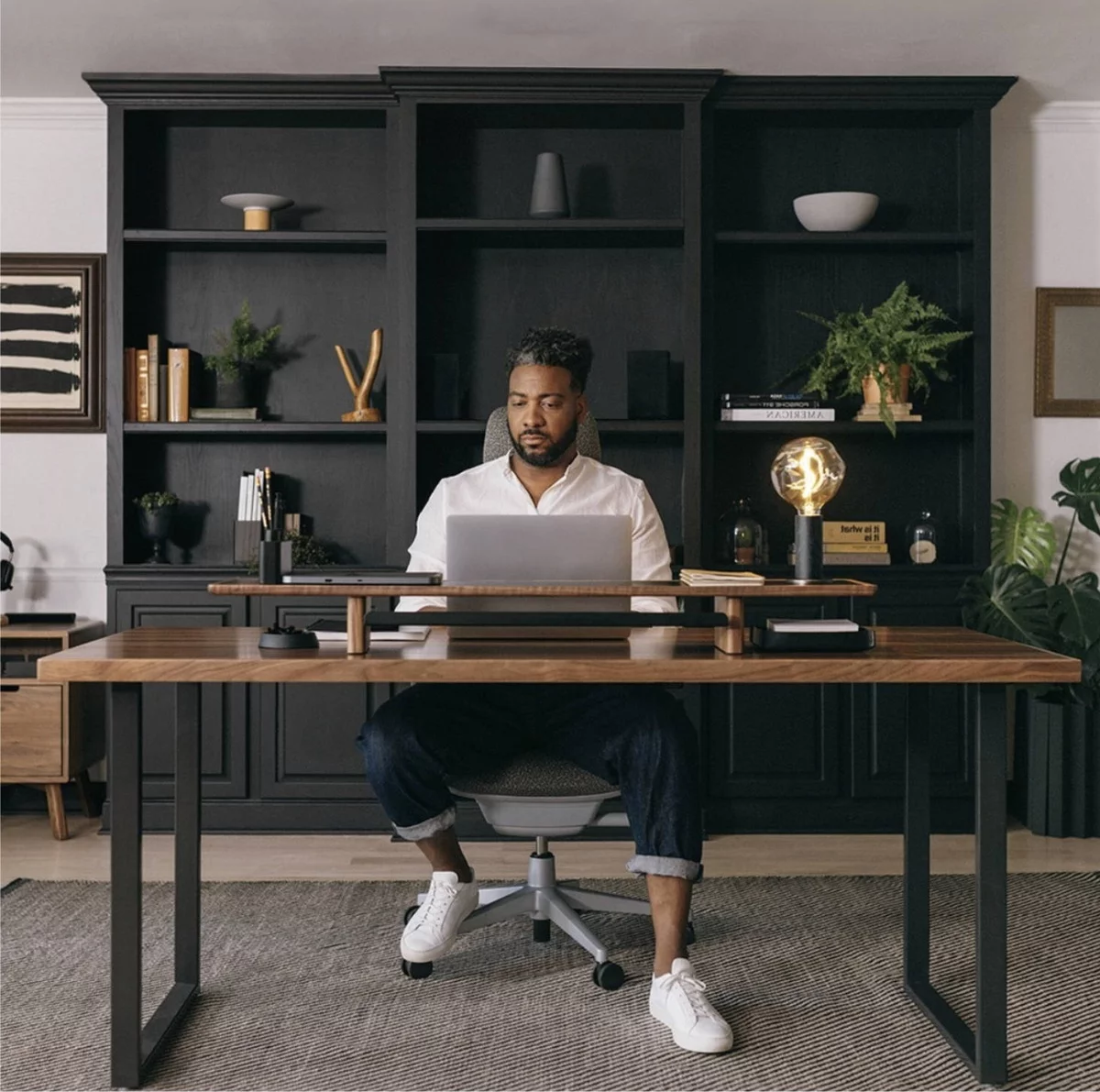 junger Mann arbeitet in männlich eingerichtetem Arbeitszimmer in dunklen Farben 