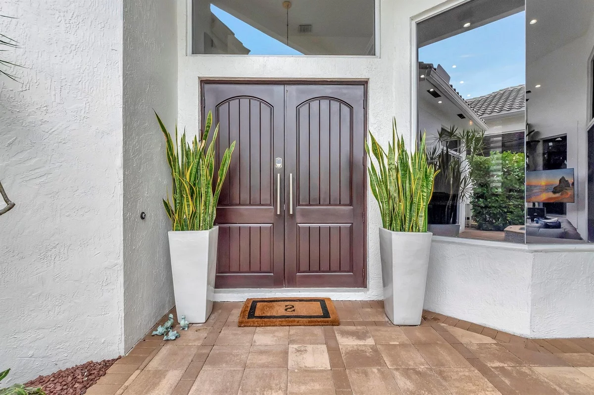 zwei hohen Blumenkästen mit grünen Pflanzen beiderseits der Haustür