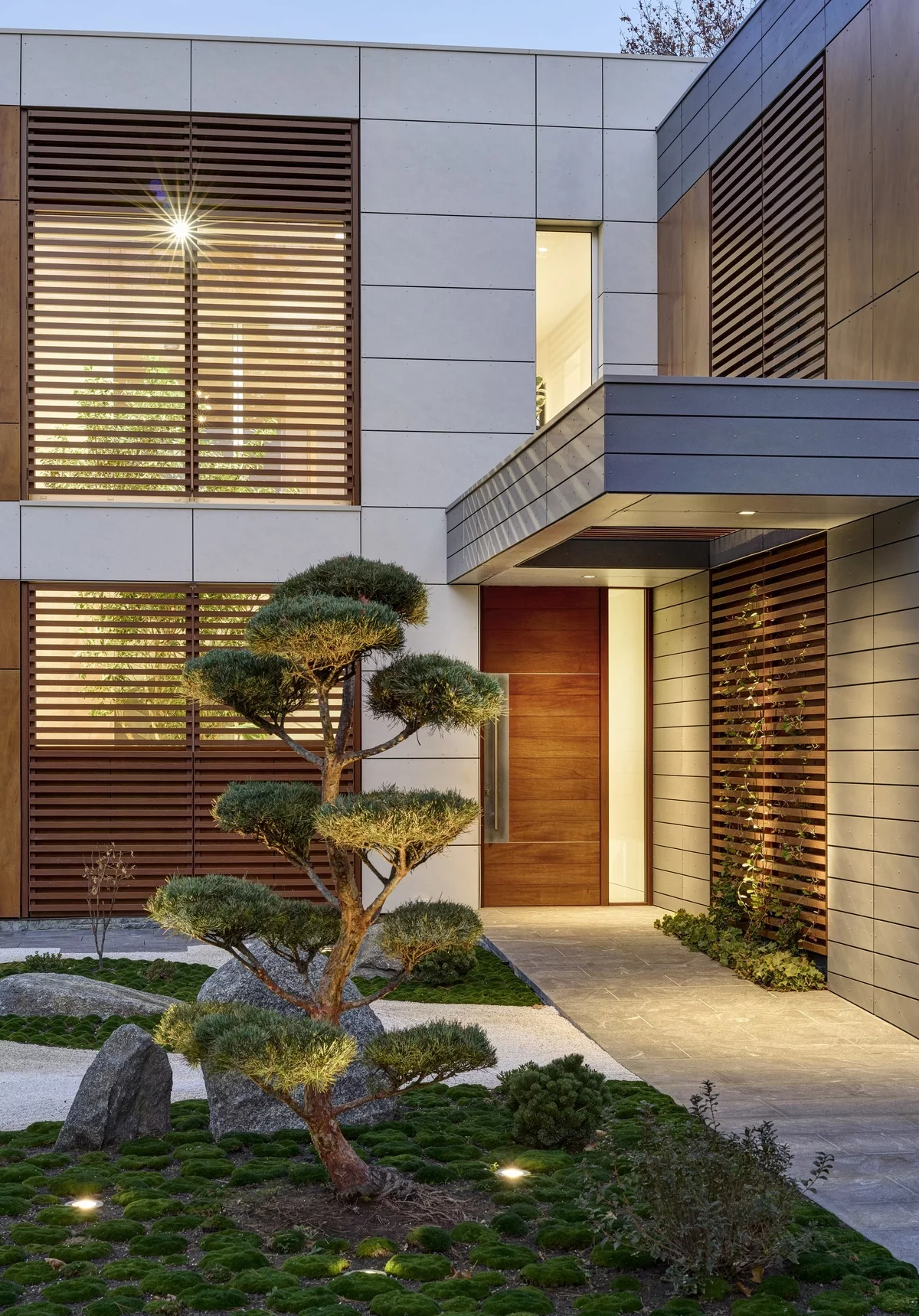 Hauseingang im fernöstlichen Stil gestaltet mit Bonsai Pflanze draußen zwischen den Steinen