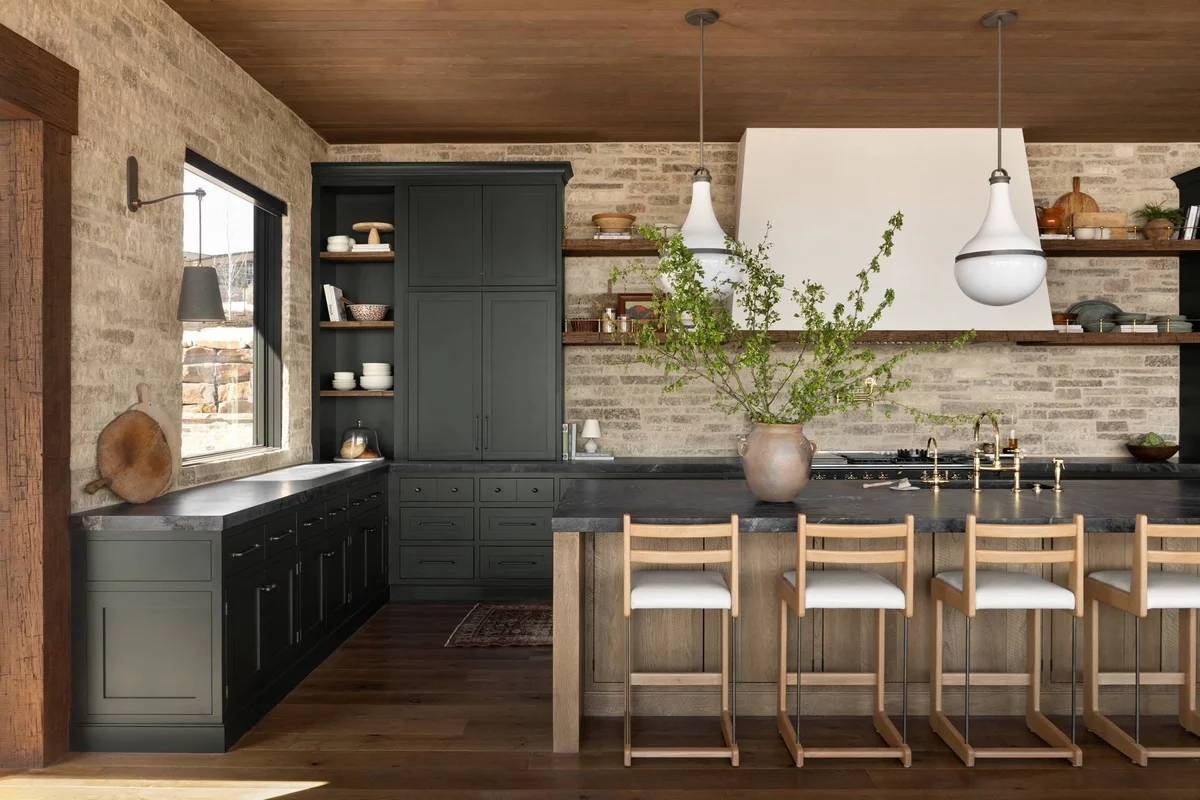 sehr stilvoll gestaltete Küche- Steinwand, schwarze Schränke und Kücheninsel 