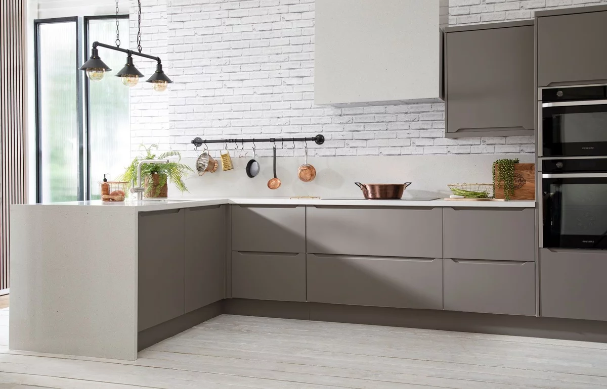 moderne Küche in Grau und Schwarz vor einer weißen Ziegelwand