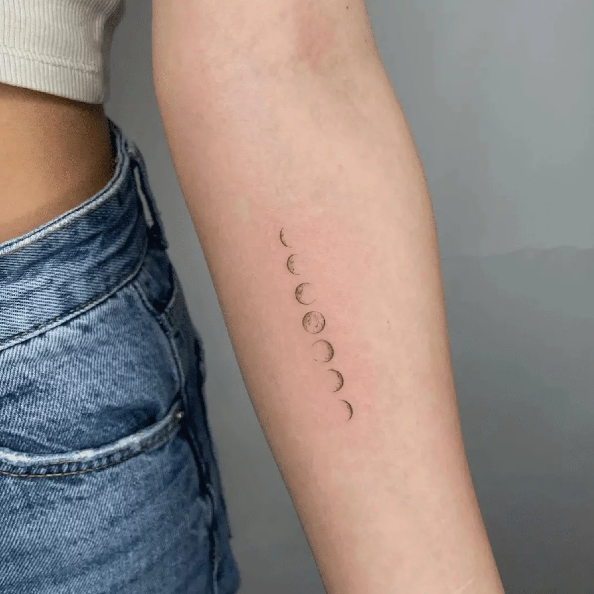 Mondphasen als minimalistisches Tattoo am Unterarm