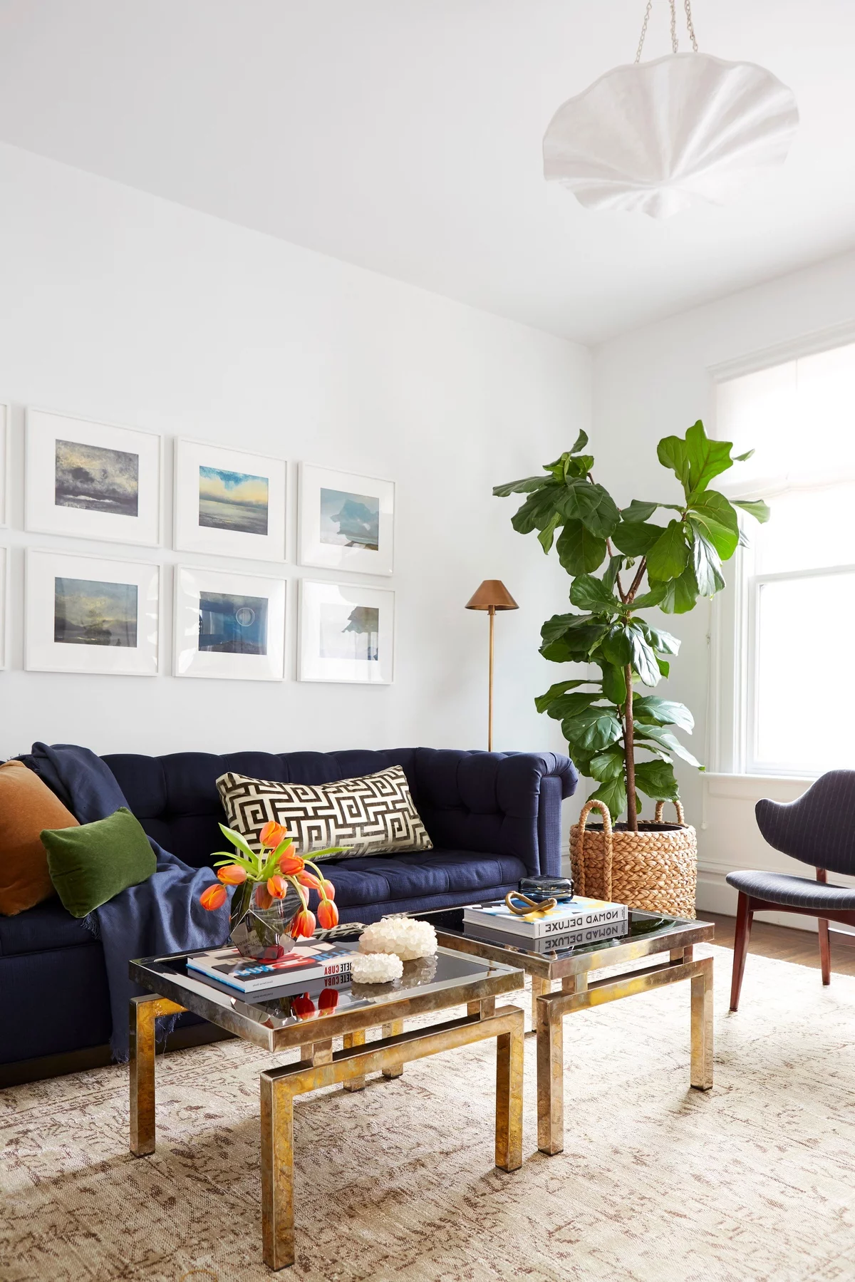 dunkelblaues Sofa als Hingucker im Wohnzimmer, Wandbilder und grüne Topfpflanze als Akzente