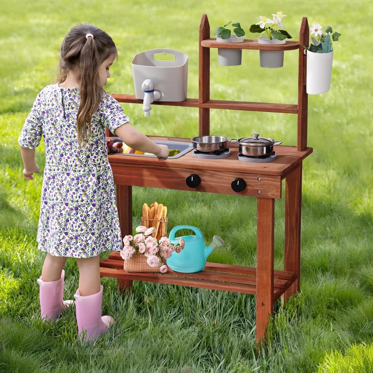 kleines Mädchen spielt im Garten neben ihrer Matschküche