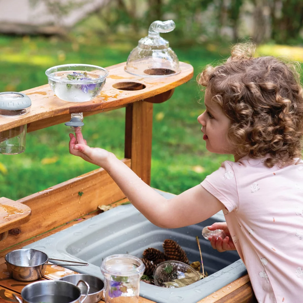 kleines Mädchen kocht mit Naturmaterialien - Matschküche für Kinder