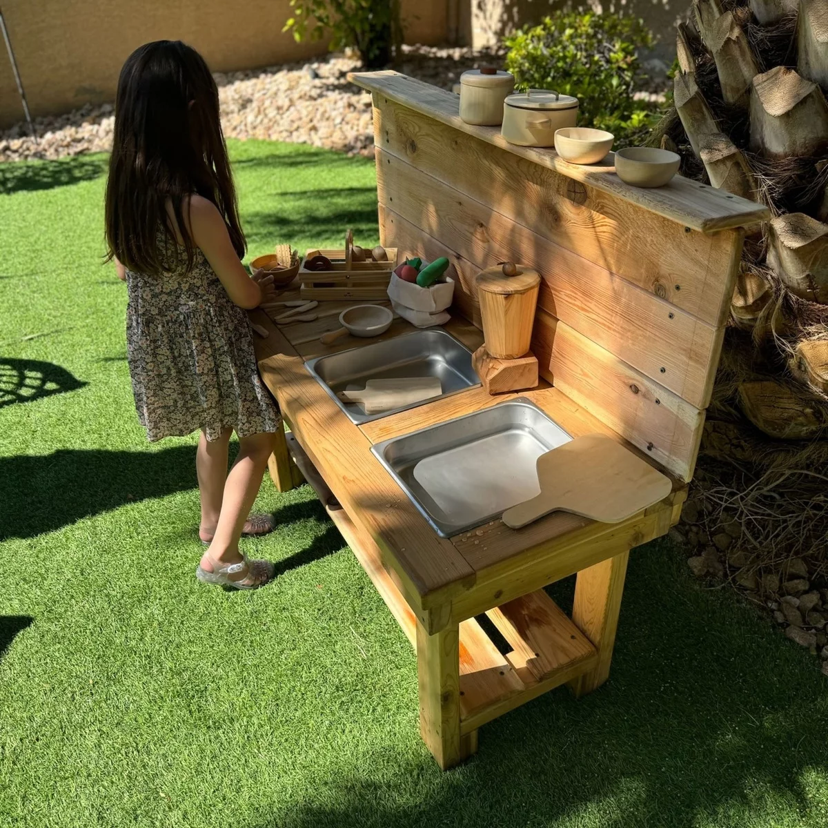 kleines Mädchen spielt im Garten an ihrer Matschküche