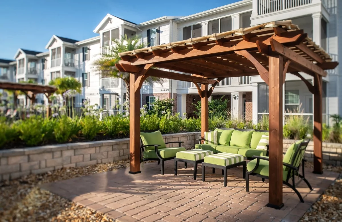 Gartenlaube aus Holz auf Terrasse mit hellgrünen Outdoor-Möbeln 