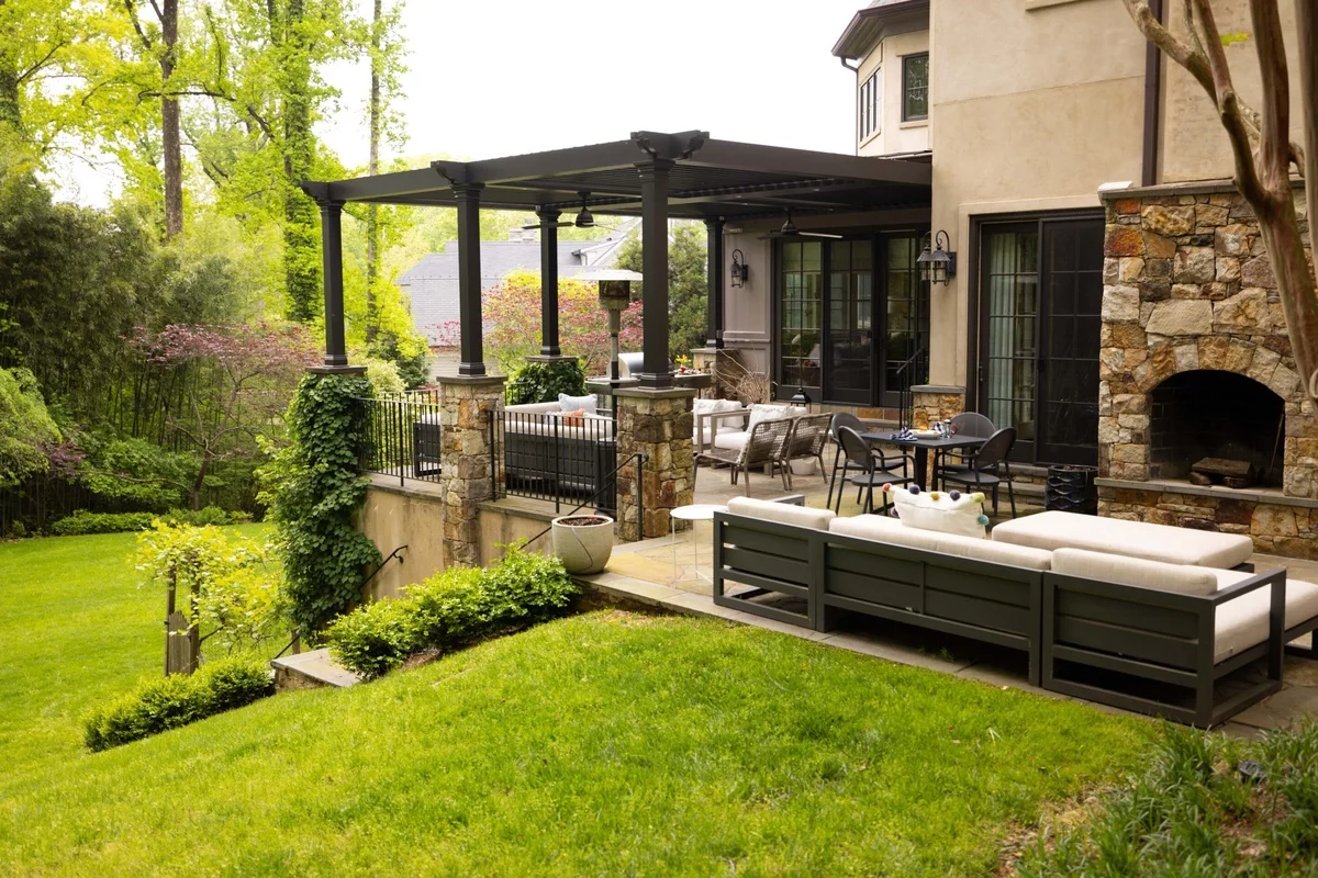 moderne Gartenlaube mit Sitzbereich unter dem Dach daneben Kamin und Outdoor-Couch 