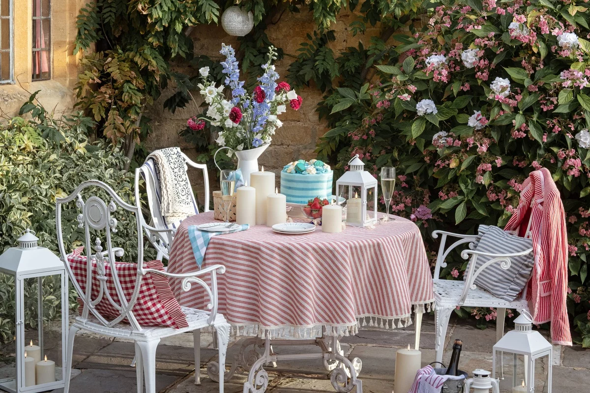 Shabby Chic Garten gestalten - runder Tisch mit gestreifter Decke und Stühle aus Metall 