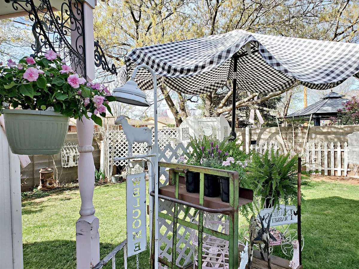 Gartenlaube mit Blumenkasten und ein karierter Sonnenschirm vorne