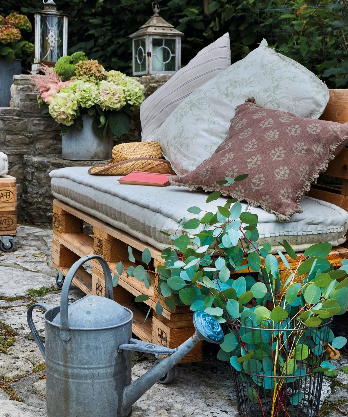 SGartensofa aus Paletten mit bequemen Kissen - viel Grün ringsum 