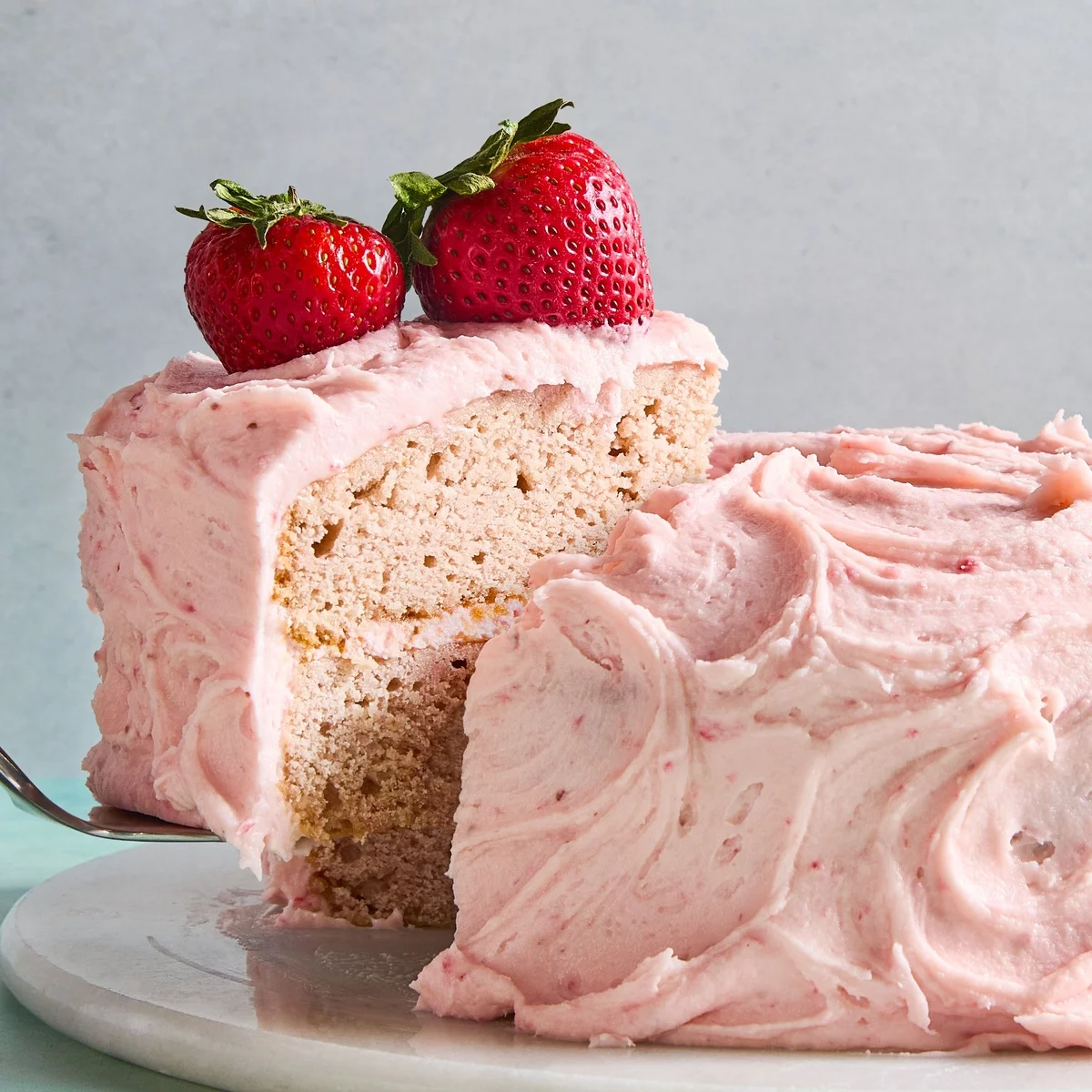 ein leckeres Stück rosa Erdbeerkuchen mit zwei frischen Erdbeeren darauf