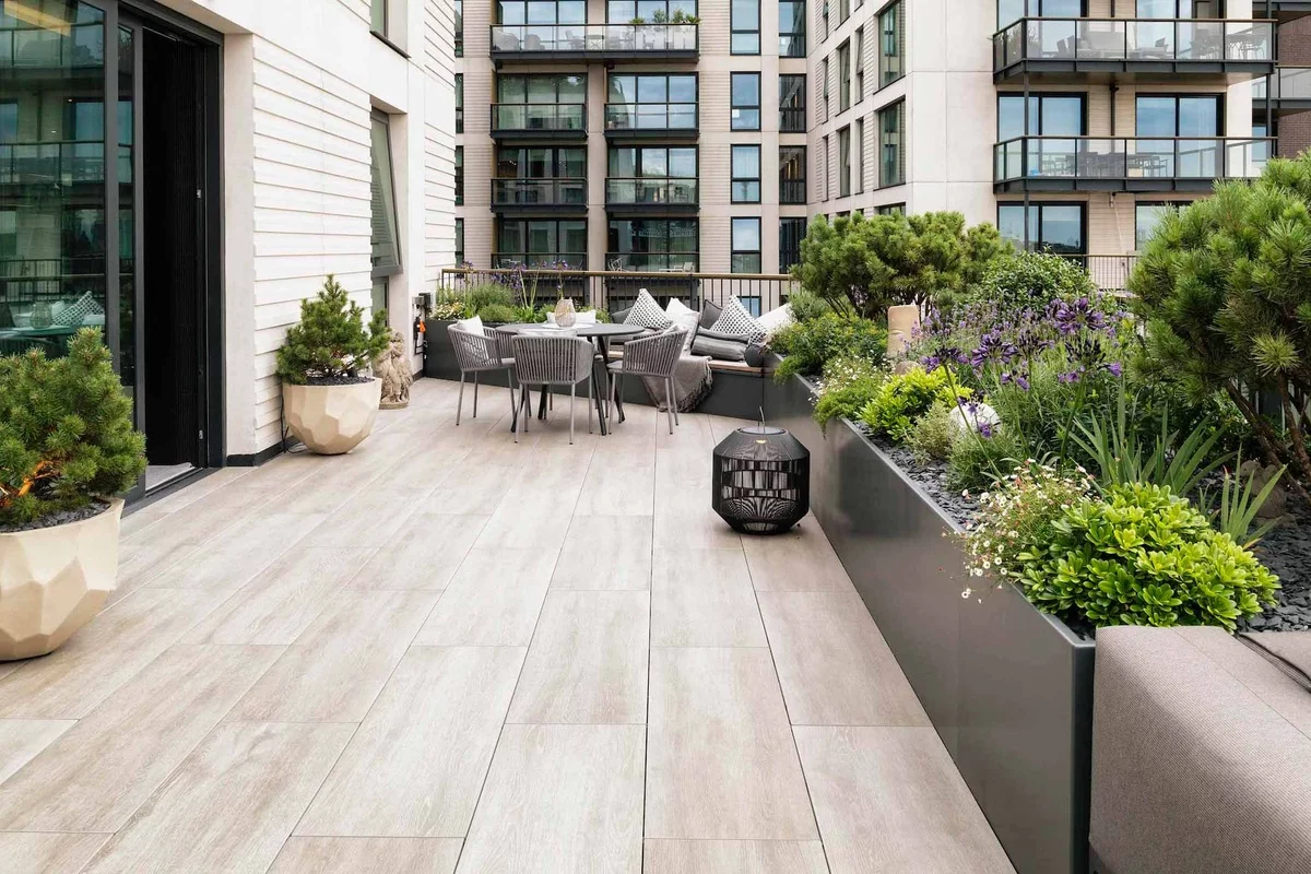 weite Terrasse in der Stadt mit Essecke und vielen grünen Topfpflanzen 