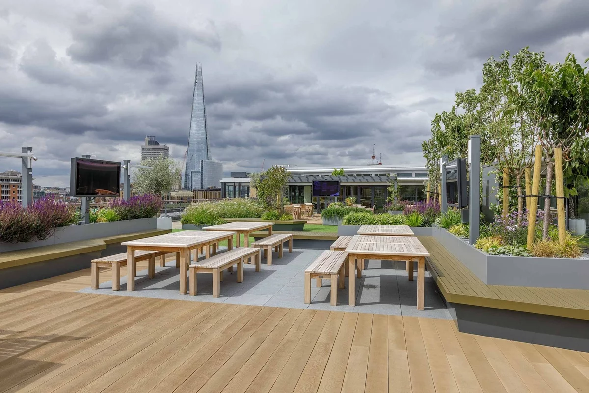 Dachterrasse in der Stadt mit Holztischen und Stühlen gestaltet 