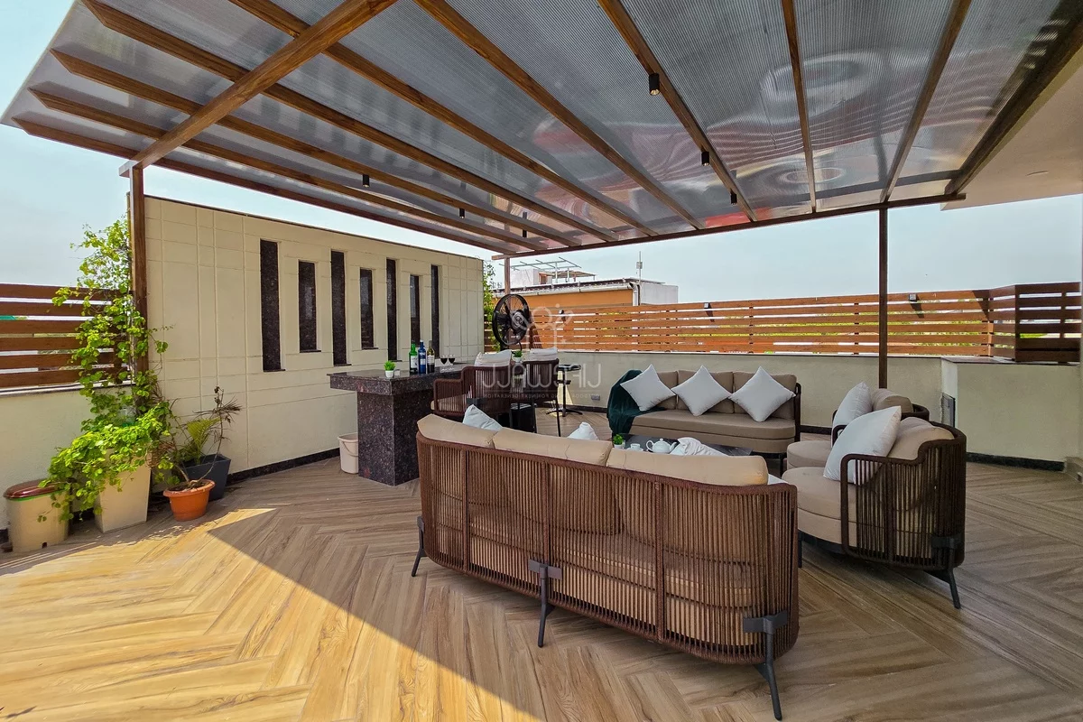 weite Terrasse mit Outdoor-Küche und Sitzecke unter Überdachung gestaltet